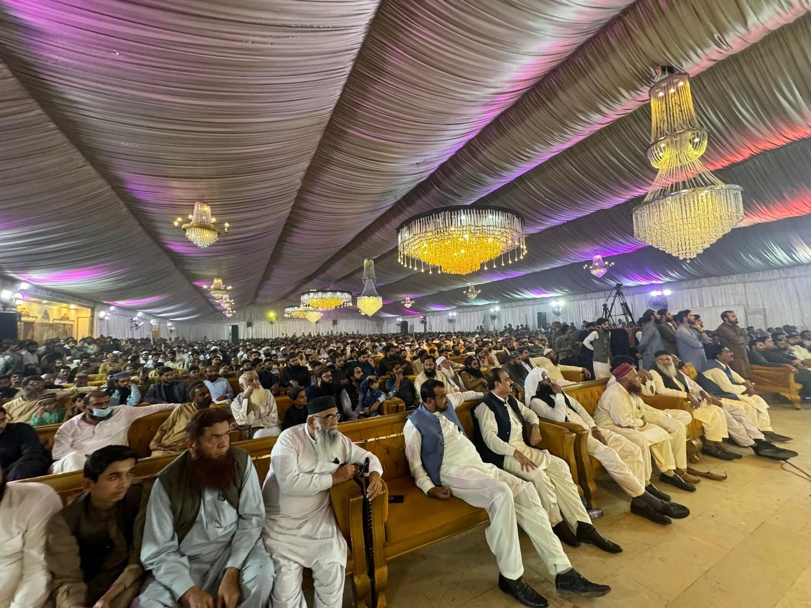 Focused view of guests seated under draped ceiling at the Mailsi event