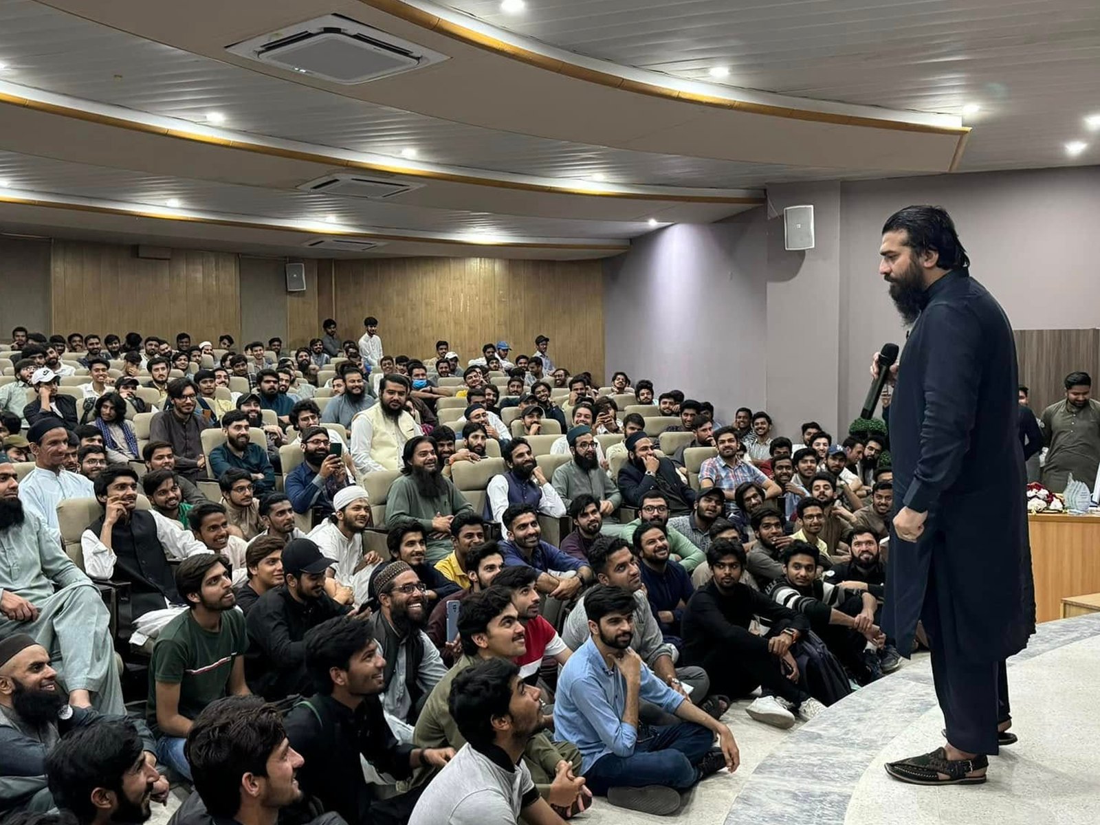 Packed hall with speaker and students on the side view at Youth Session, UOL