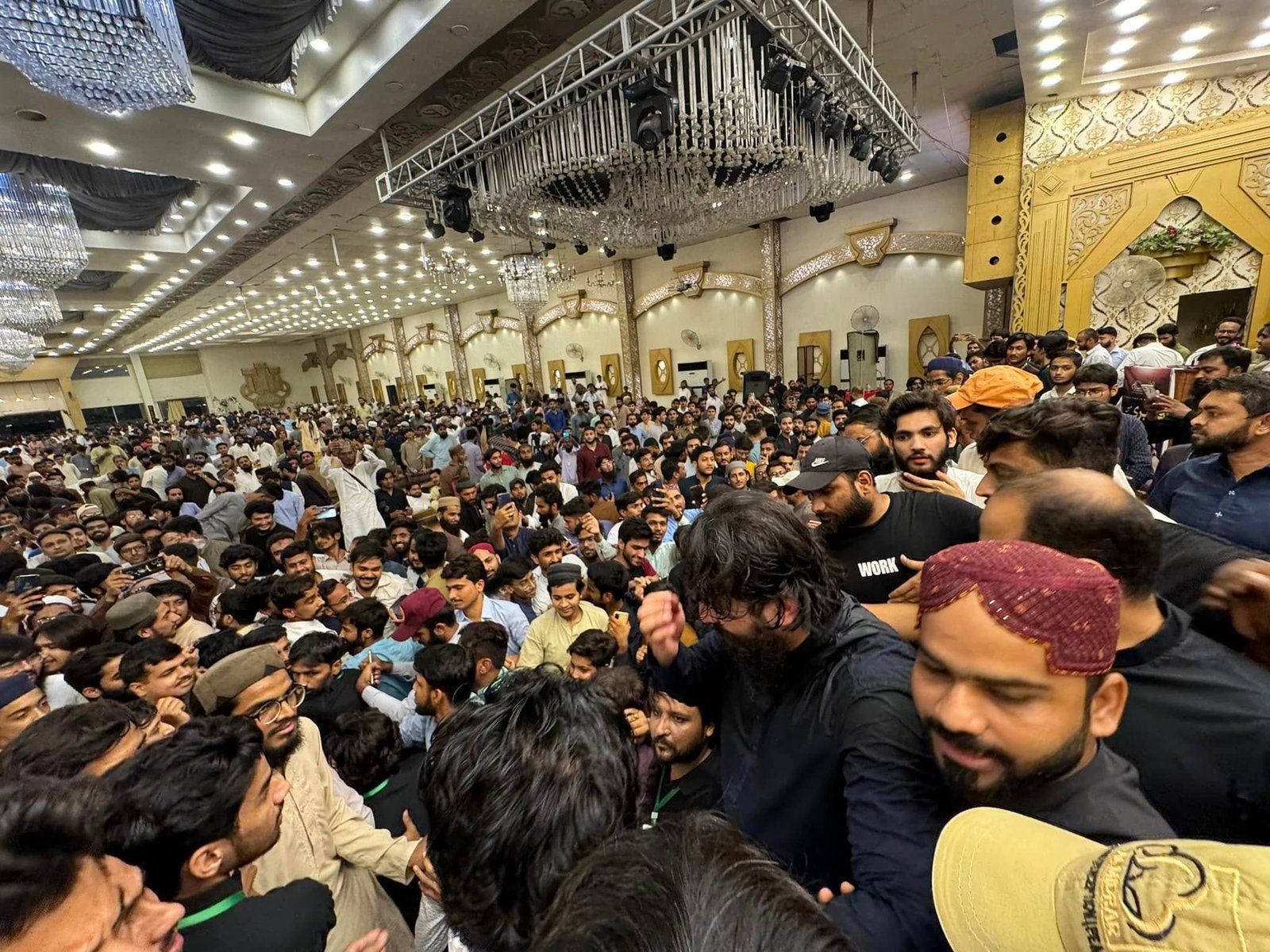 Wide view of decorated hall with full audience and chandeliers