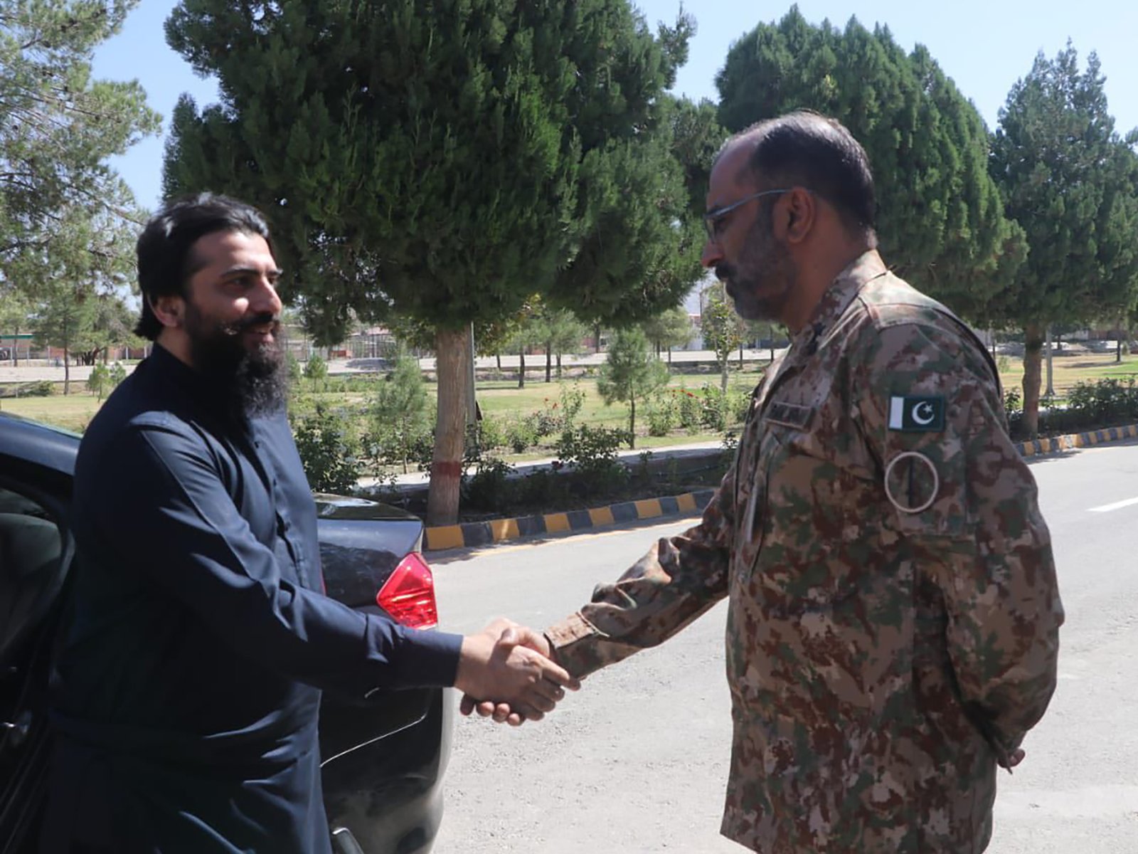 Civilian exchanging handshake with officer in an outdoor setting
