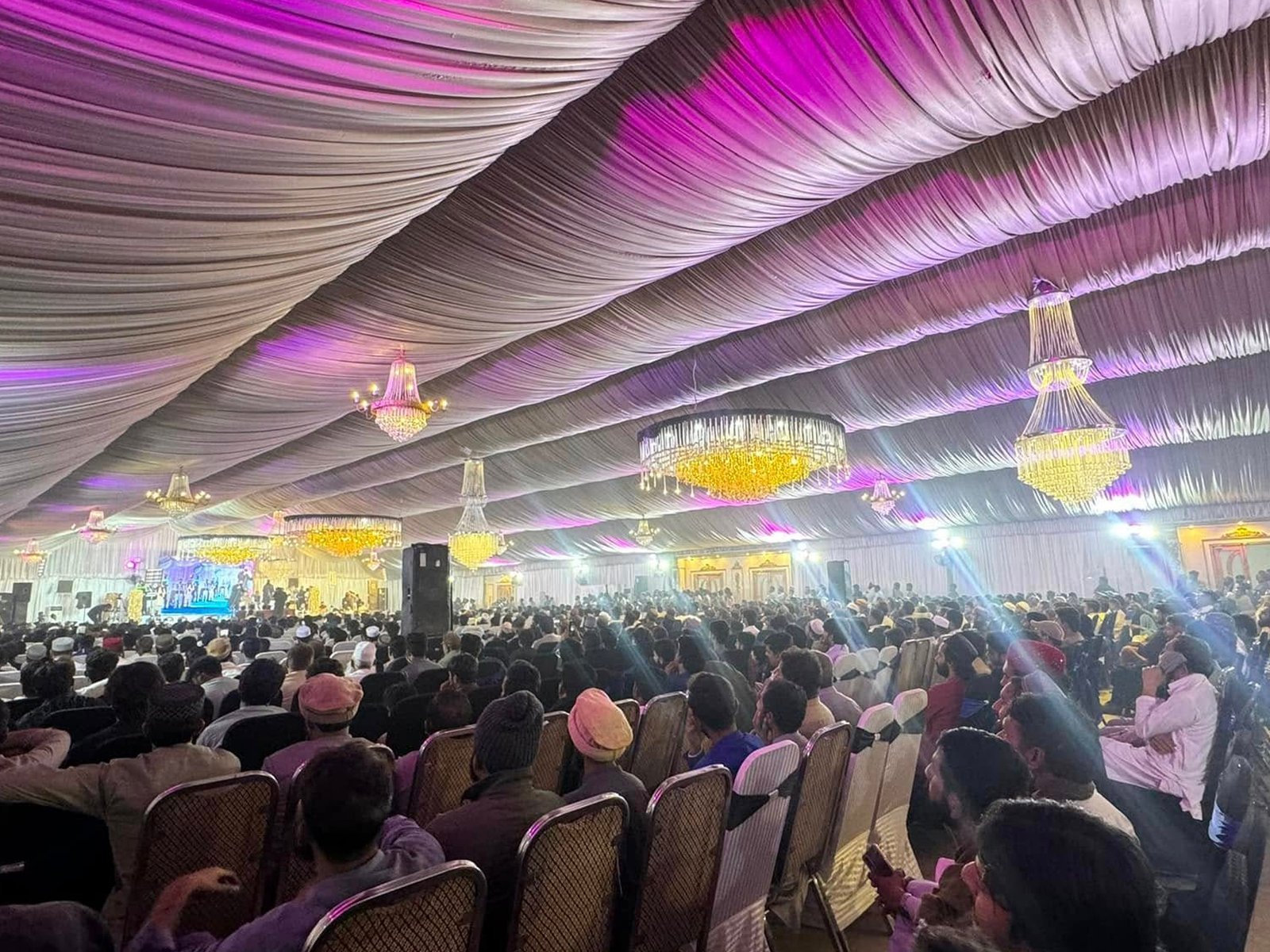 Decorated marquee with full crowd, lights, and overhead drapes