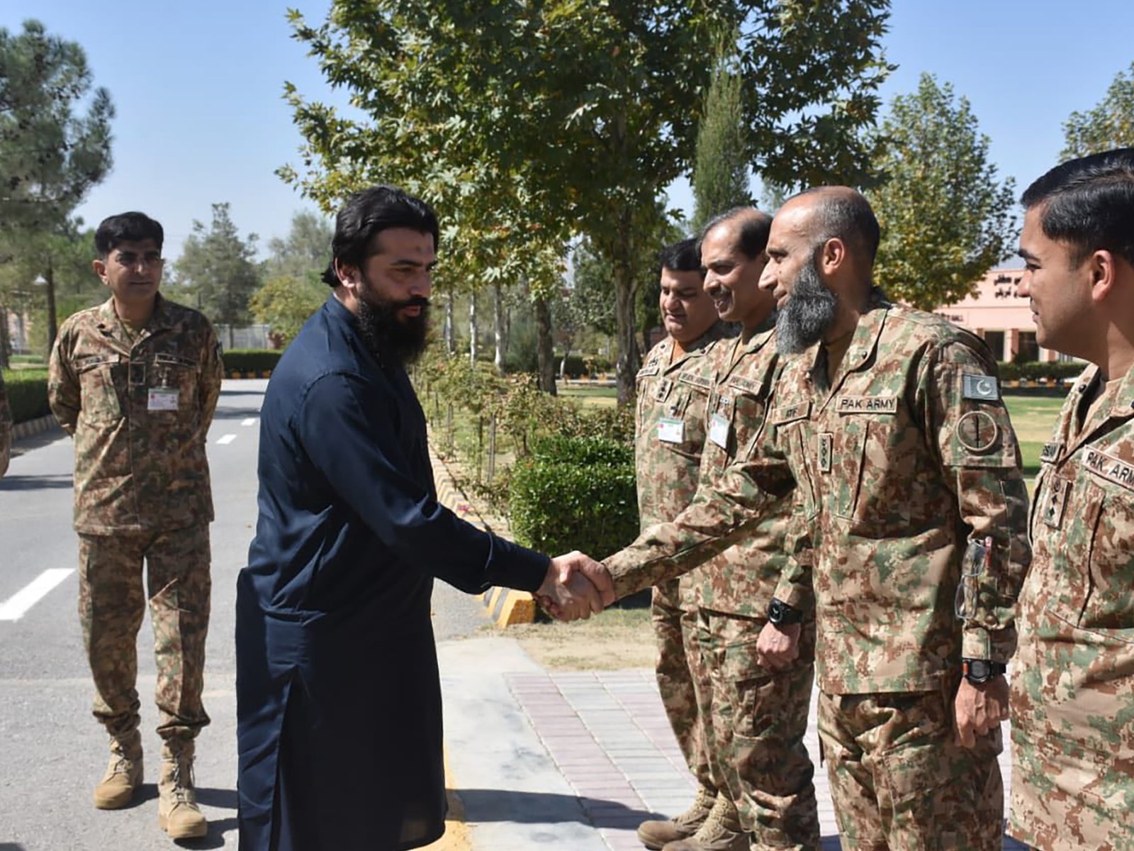 Guest of honor shaking hands with military personnel at event entrance